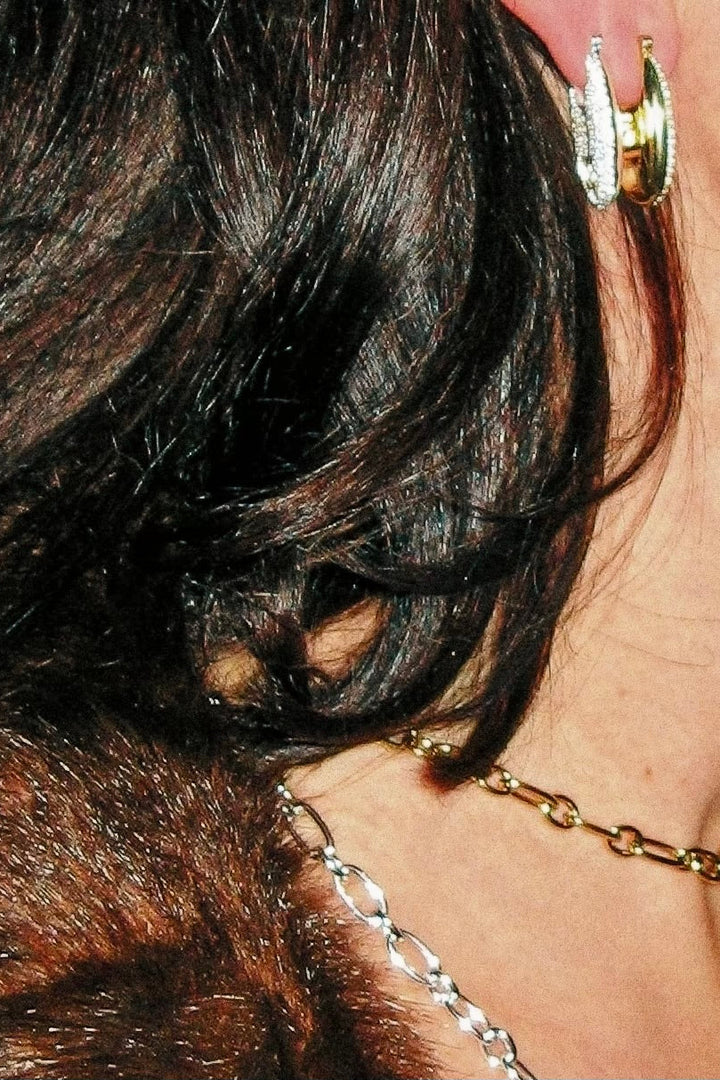 Close-up of an ear with a gold earring and necklace